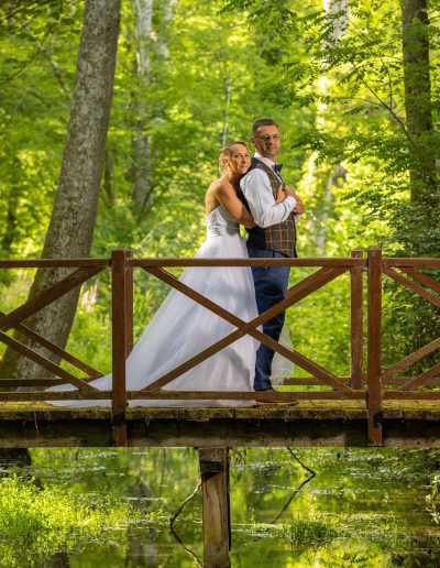 Portrait de mariés romantique sur un pont en bois au-dessus de l'eau, shooting mariage en Sologne